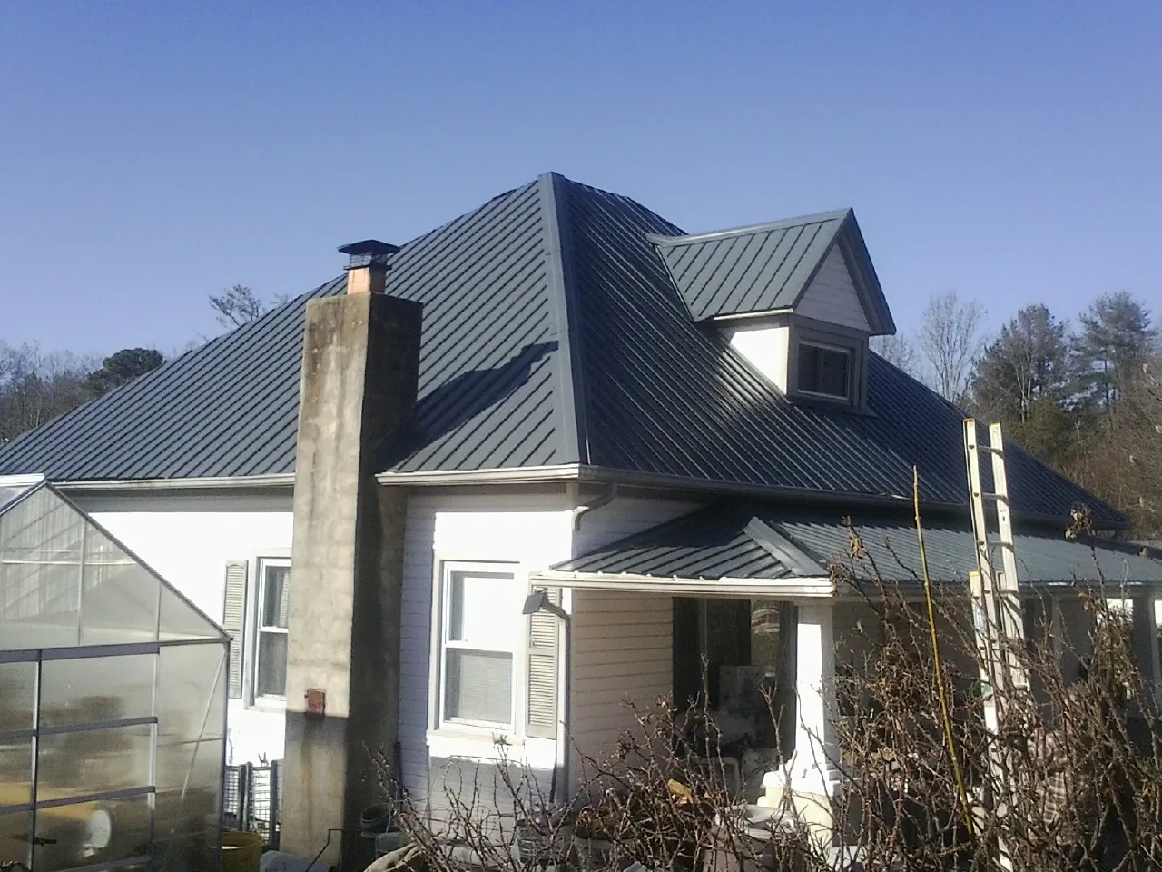 Dark blue standing seam metal roof on a white farmhouse with dormer — Slate & Tile Roof Repair by Roofing Brothers in Mount Wolf
