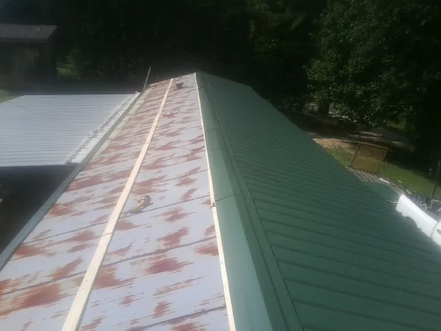 Old rusted panels beside newly installed green metal roofing — Wind Damage Roof Repair by Roofing Brothers in Mount Wolf