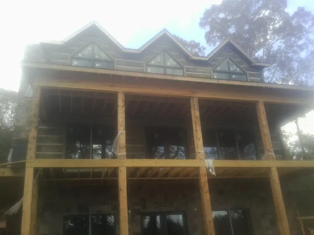 Dormers and porch framing on a large log home under construction — Roof Coating work by our crew in Mount Wolf