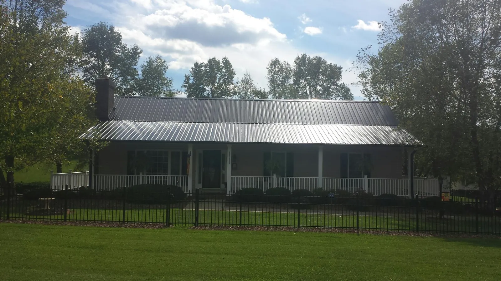 Gray metal roof on a brick ranch with a full width front porch — Gutter Guard Installation work by our crew in Mount Wolf