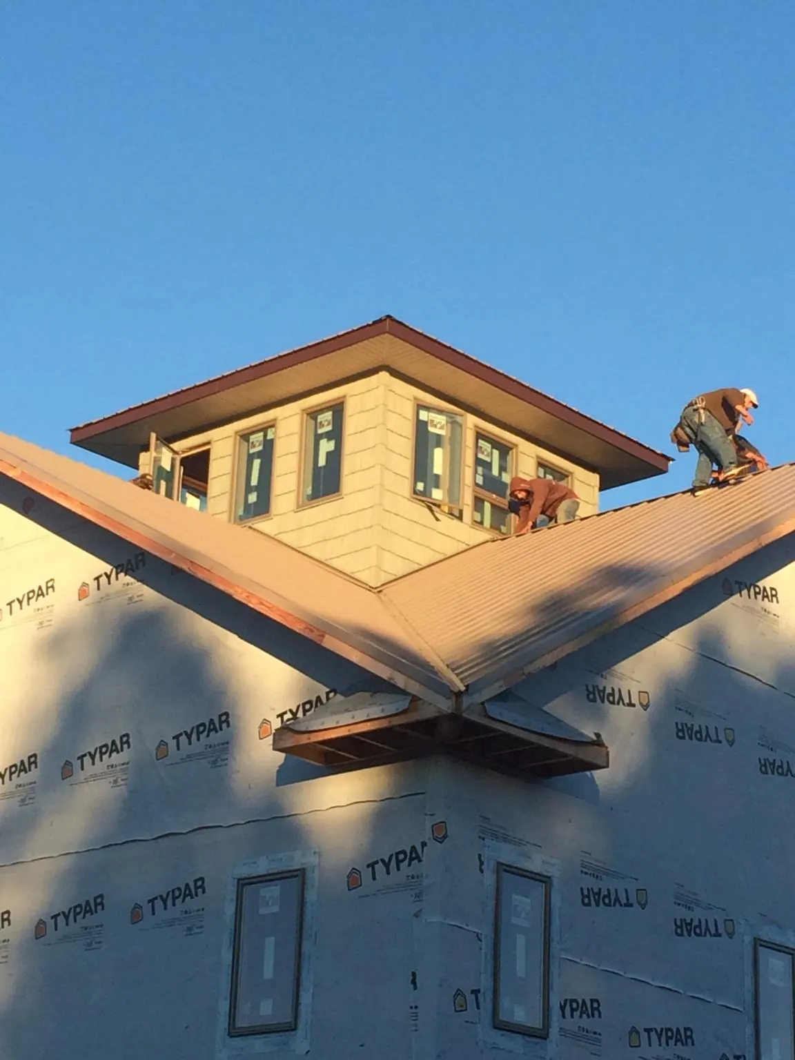 Roofers working around a rooftop cupola on a new metal roof at sunset — Roof Waterproofing in Mount Wolf by Roofing Brothers
